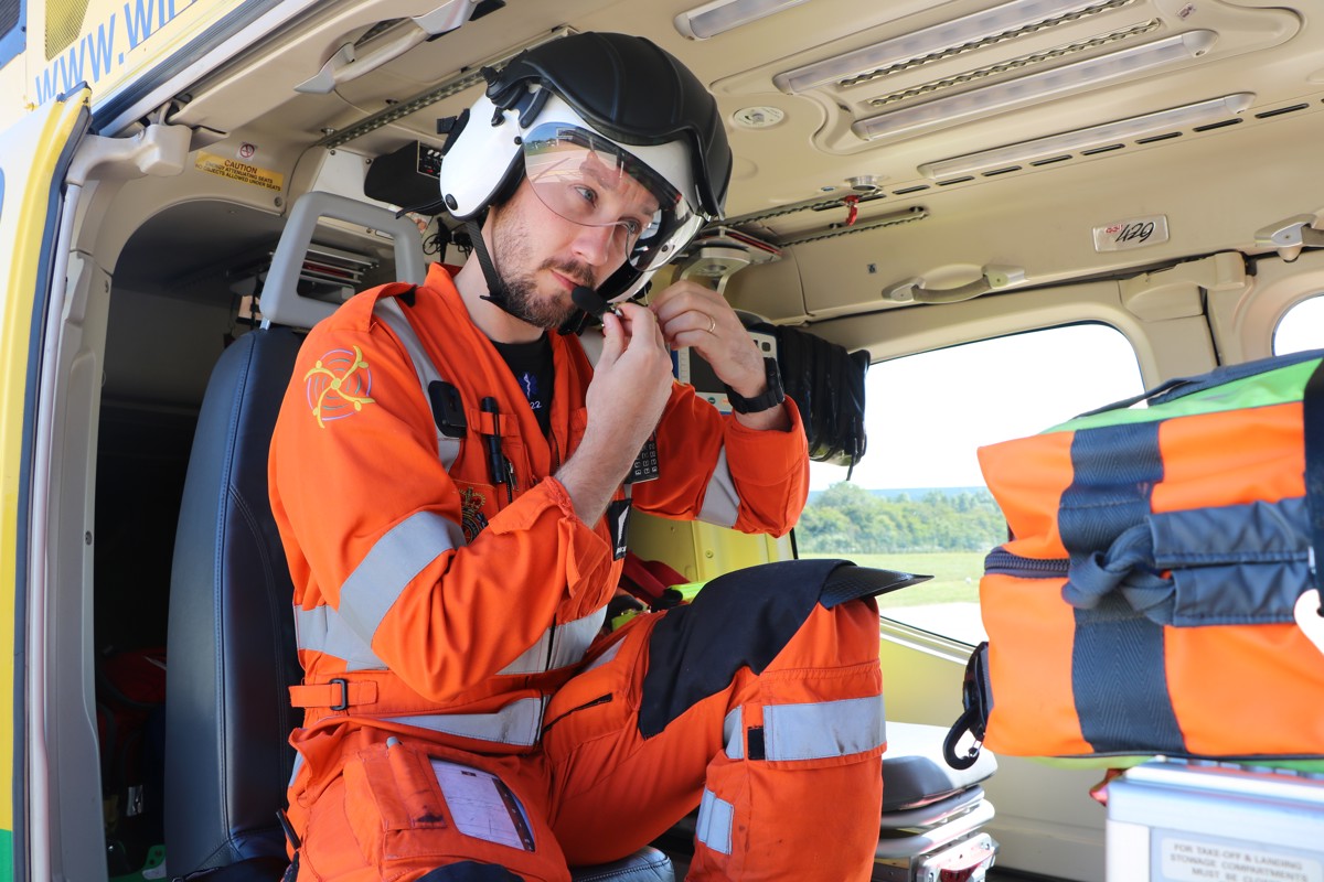 A photo of doctor Jono Holme securing his helmet, whilst sat in the helicopter A photo of doctor Jono Holme securing his helmet, whilst sat in the helicopter