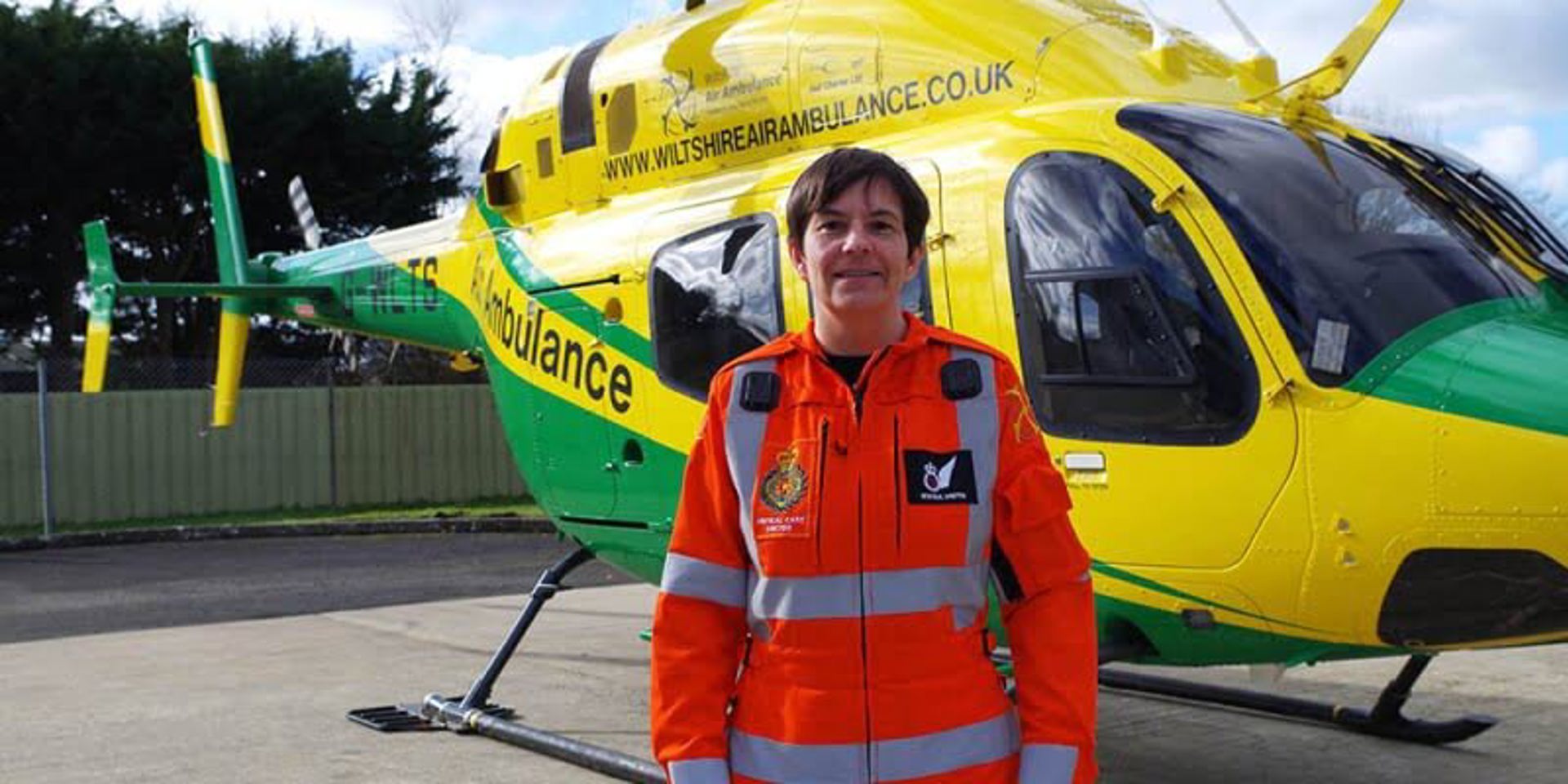 A critical care doctor wearing a flight suit in front of the Wiltshire Air Ambulance helicopter. A critical care doctor wearing a flight suit in front of the Wiltshire Air Ambulance helicopter.