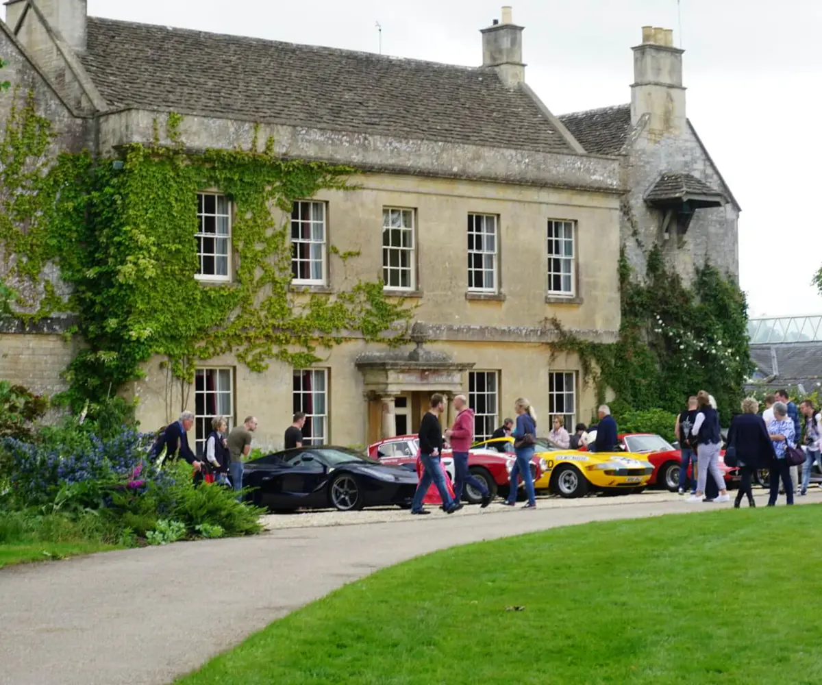 A photo of Middlewick House with sports cars parked outside and visitors taking photos and looking at the cars.
