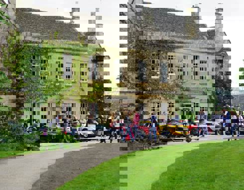 A photo of Middlewick House with sports cars parked outside and visitors taking photos and looking at the cars.