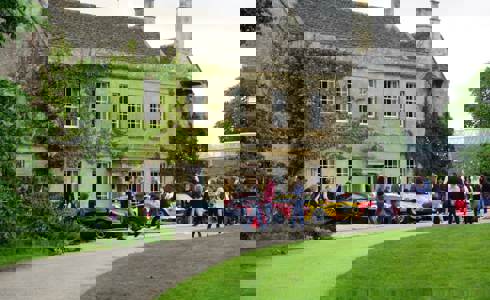 A photo of Middlewick House with sports cars parked outside and visitors taking photos and looking at the cars. A photo of Middlewick House with sports cars parked outside and visitors taking photos and looking at the cars.