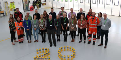 A photo of charity team members with yellow collection tins arranged in the number 20. A photo of charity team members with yellow collection tins arranged in the number 20.