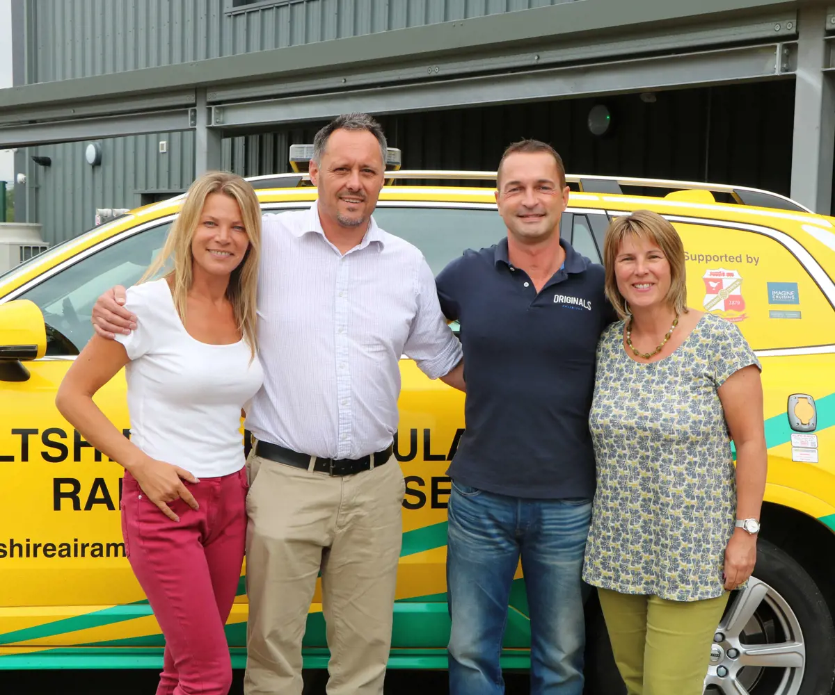 A former patient and their partner visiting Wiltshire Air Ambulance, the group are with a paramedic and pilot stood in front of the critical care car. A former patient and their partner visiting Wiltshire Air Ambulance, the group are with a paramedic and pilot stood in front of the critical care car.