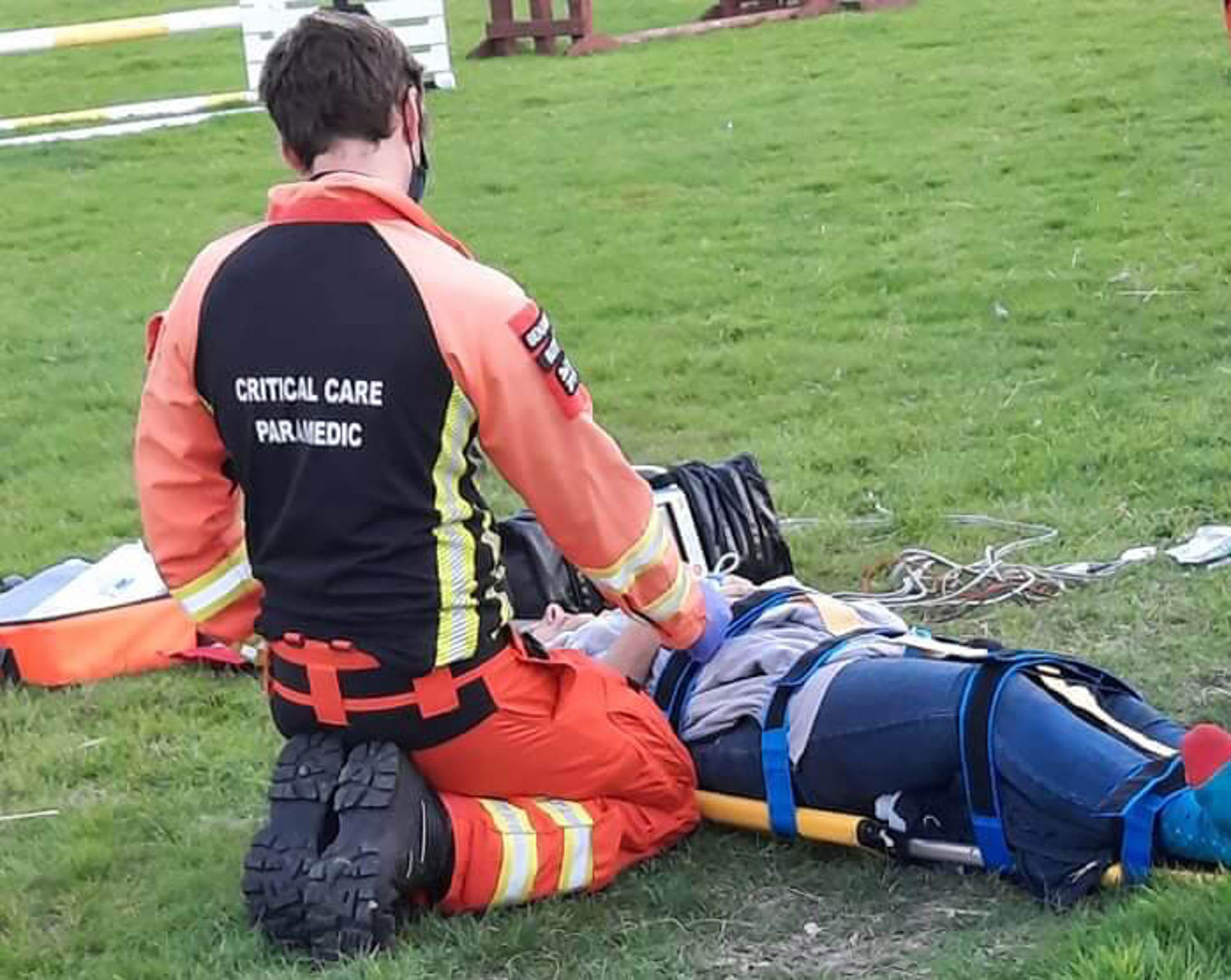 A patient laying on a stretcher with a critical care paramedic knelt by their side A patient laying on a stretcher with a critical care paramedic knelt by their side