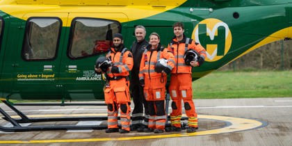 A group of air ambulance colleagues standing in front of a yellow and green helicopter