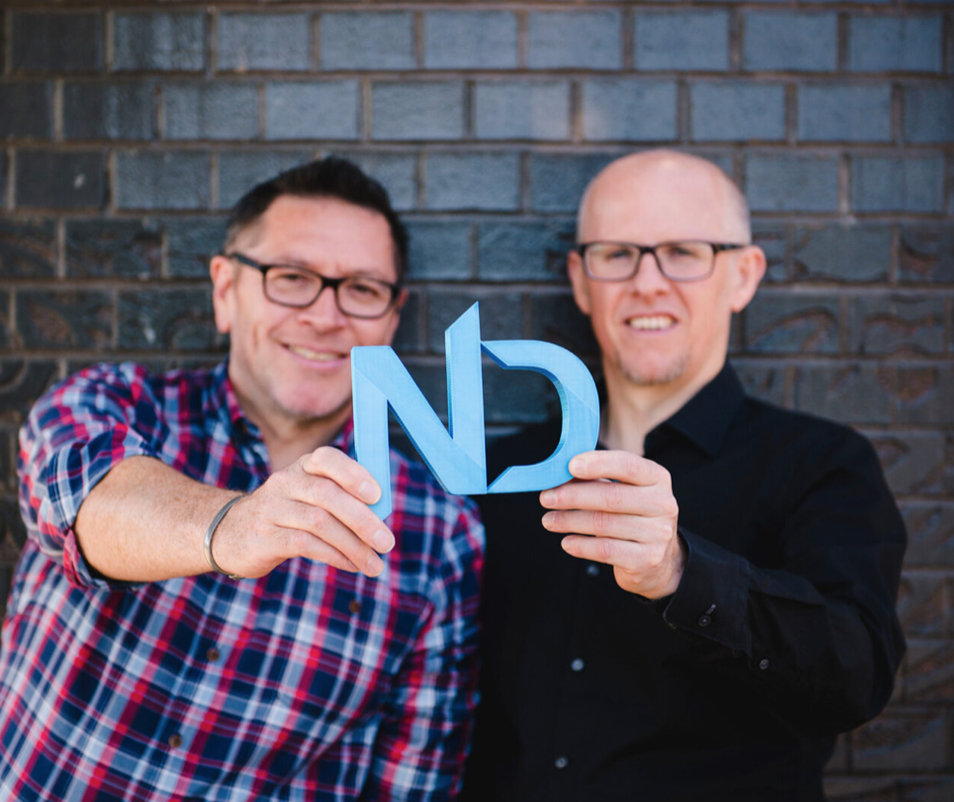 Two people holding a sign which is blue and has the letters N and D Two people holding a sign which is blue and has the letters N and D