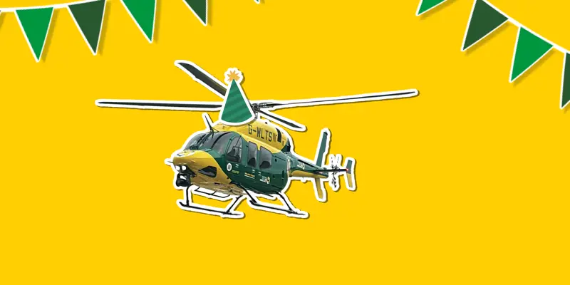 A yellow background with a sticker of the yellow and grey Bell 429 helicopter wearing a cartoon sticker hat, with green bunting around it