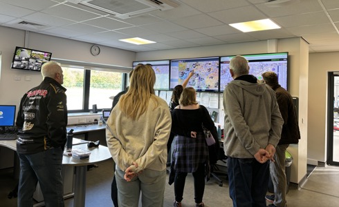A group of people being shown screens in a flight room A group of people being shown screens in a flight room