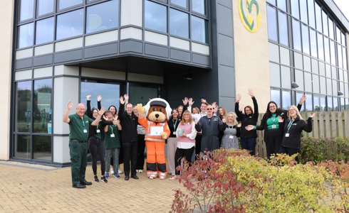 The charity team and mascot celebrating outside the airbase holding a vase award and certificate The charity team and mascot celebrating outside the airbase holding a vase award and certificate
