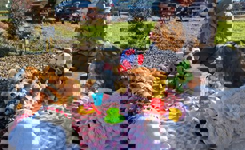 Young children sat with a parent on a picnic blanket with toys, overlooking an airbase Young children sat with a parent on a picnic blanket with toys, overlooking an airbase