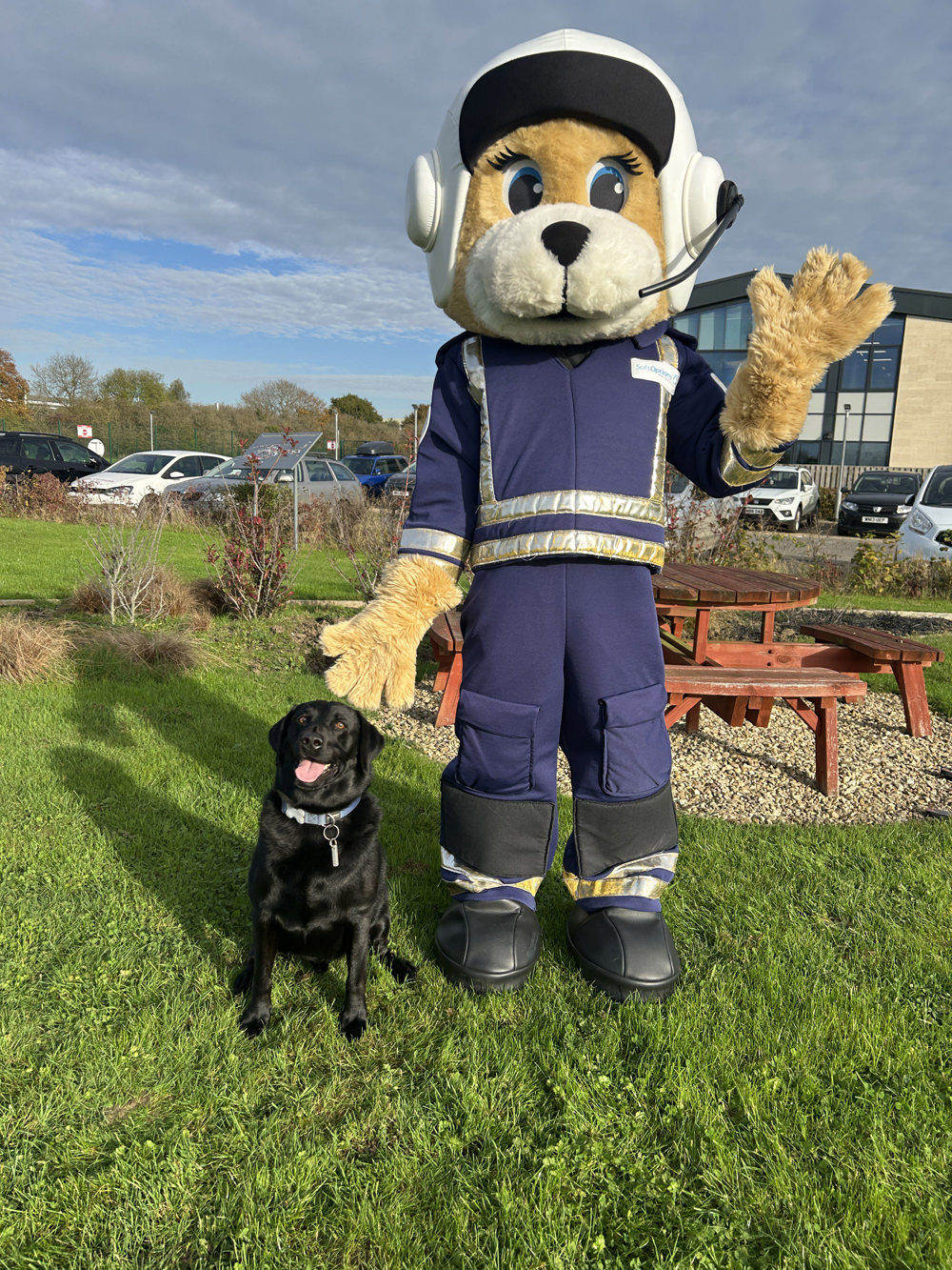 Air Ambulance pilot mascot standing with a black Labrador outside the airbase Air Ambulance pilot mascot standing with a black Labrador outside the airbase