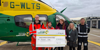 A cheque presentation with corporate beside a yellow and green helicopter A cheque presentation with corporate beside a yellow and green helicopter