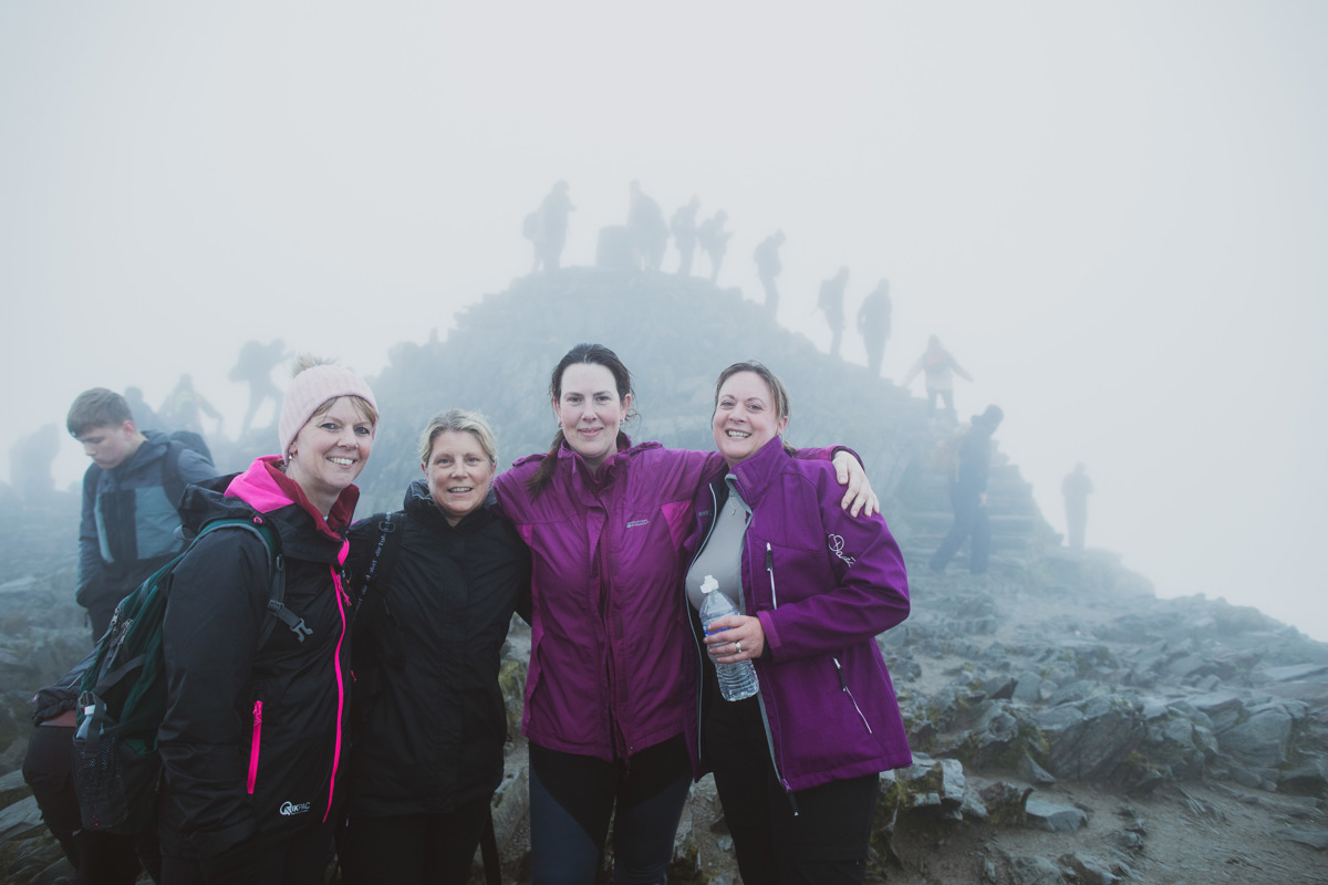 A group of 4 women posing for a photo at the top of Mount Snowdon A group of 4 women posing for a photo at the top of Mount Snowdon