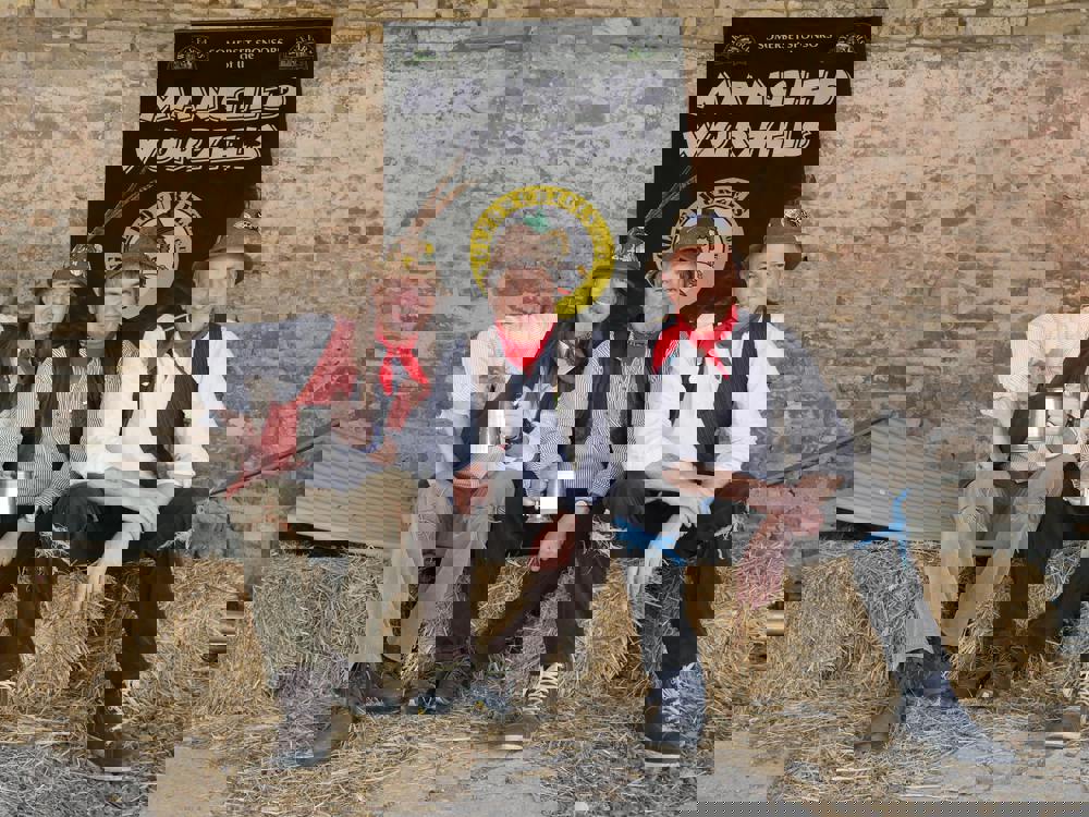 A photo of The Mangled Wurzels sitting on bales of hay A photo of The Mangled Wurzels sitting on bales of hay