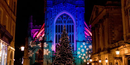 The exterior of Bath Abbey lit up with Christmas lights and a Christmas tree The exterior of Bath Abbey lit up with Christmas lights and a Christmas tree