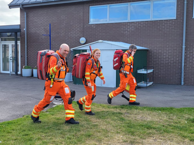 Critical care paramedics Dan Tucker and Sophie with Dr Reuben Cooper wearing flight suits and red kit bags. Critical care paramedics Dan Tucker and Sophie with Dr Reuben Cooper wearing flight suits and red kit bags.